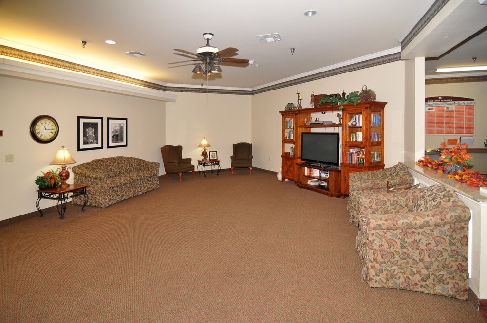 A spacious living room with sofas, a television, and a ceiling fan.