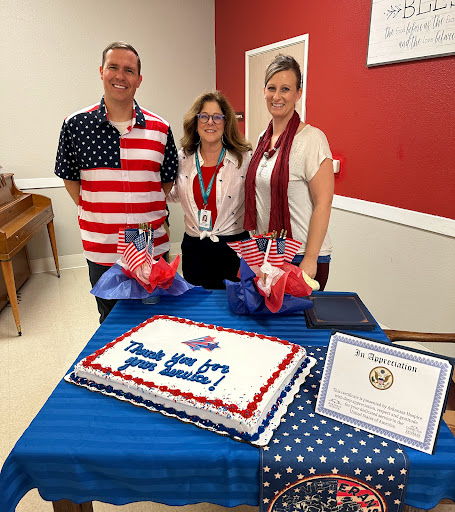 A festive gathering featuring a patriotic cake and attendees dressed in American-themed attire.