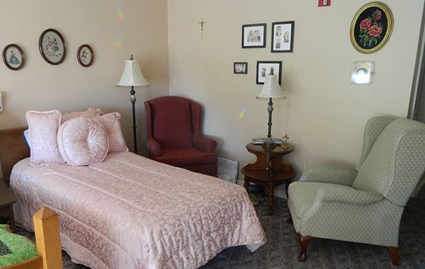 A cozy bedroom with a bed, armchair, and various decorations on the walls.