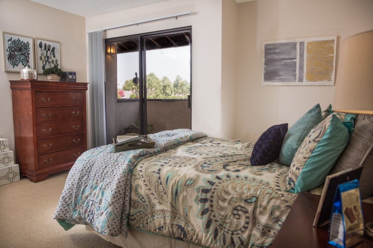 A cozy, well-decorated bedroom with a patterned bedspread and a large window.