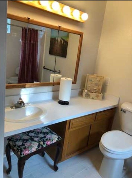 A tidy bathroom with a countertop, sink, toilet, and mirror.