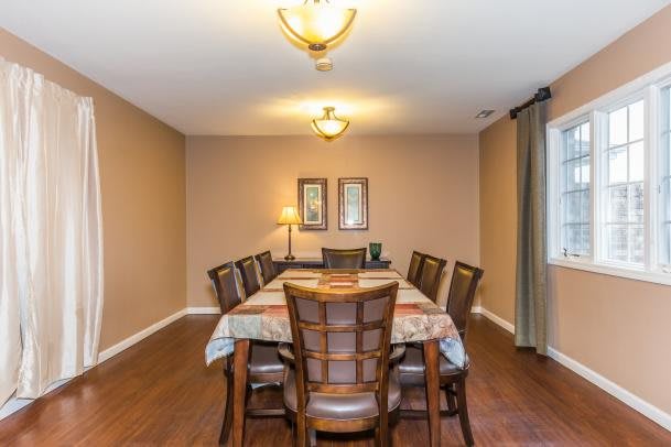 A dining room with a wood table and chairs, featuring warm lighting.