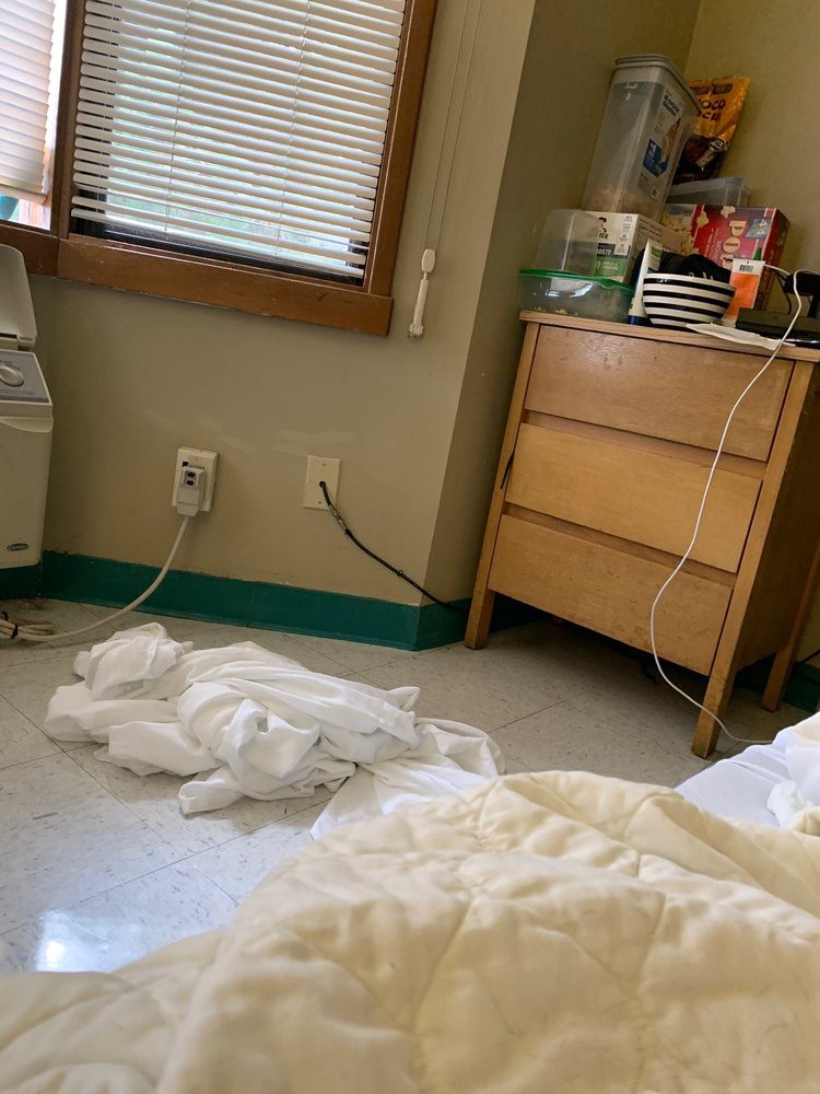 A hospital room with a dresser, cables, and a blanket on the floor.