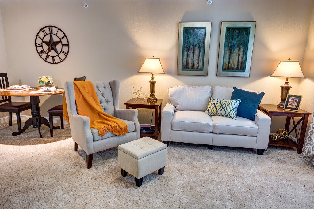A cozy living room with a sofa, armchair, and warm lighting.