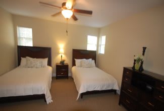 A cozy bedroom with two double beds, a ceiling fan, and warm lighting.