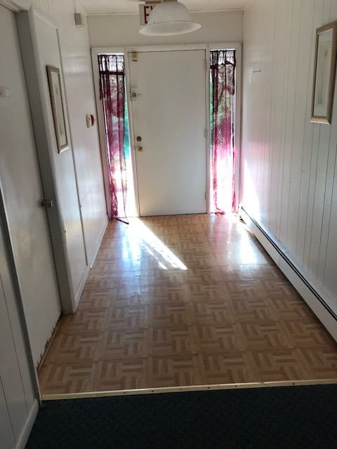 A bright hallway with wooden flooring leading to a door.