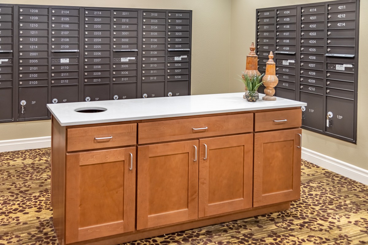 A mailroom with a wooden cabinet and rows of mailboxes in the background.