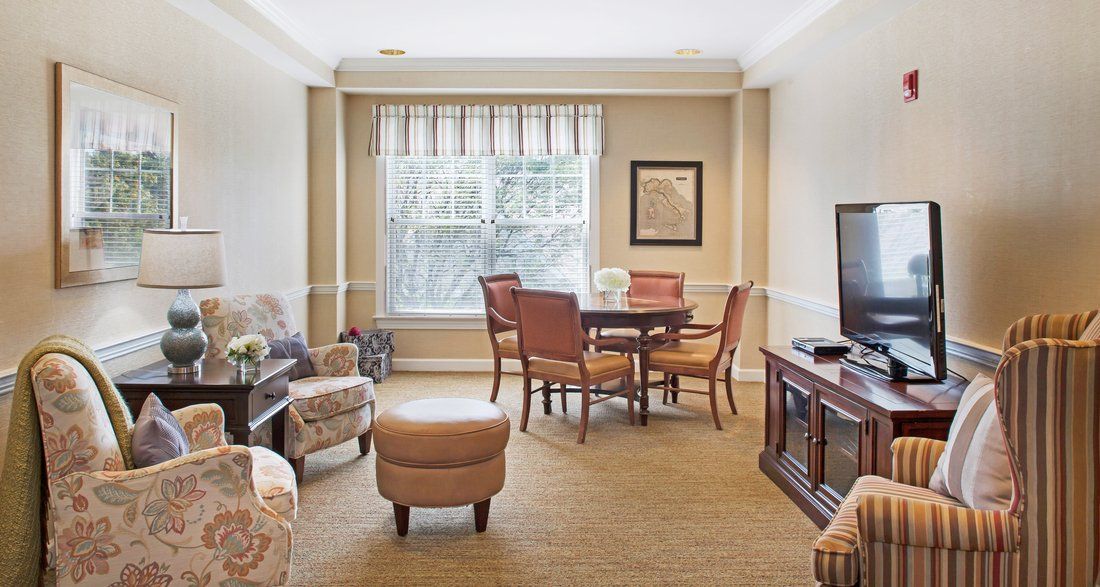 A cozy living room with a seating area and natural light streaming in through the window.