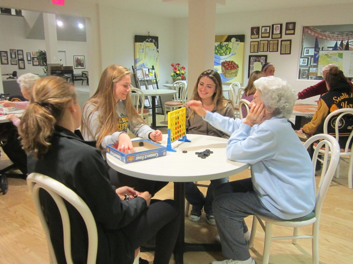 A group of people playing a board game around a table indoors.