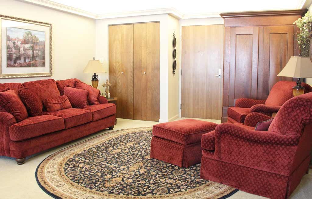 A cozy living room with red upholstered furniture and a patterned carpet.
