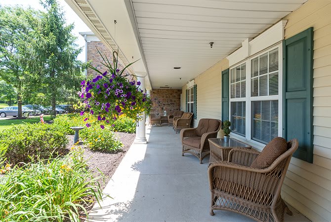 A peaceful porch with wicker chairs and hanging plants overlooks a garden.