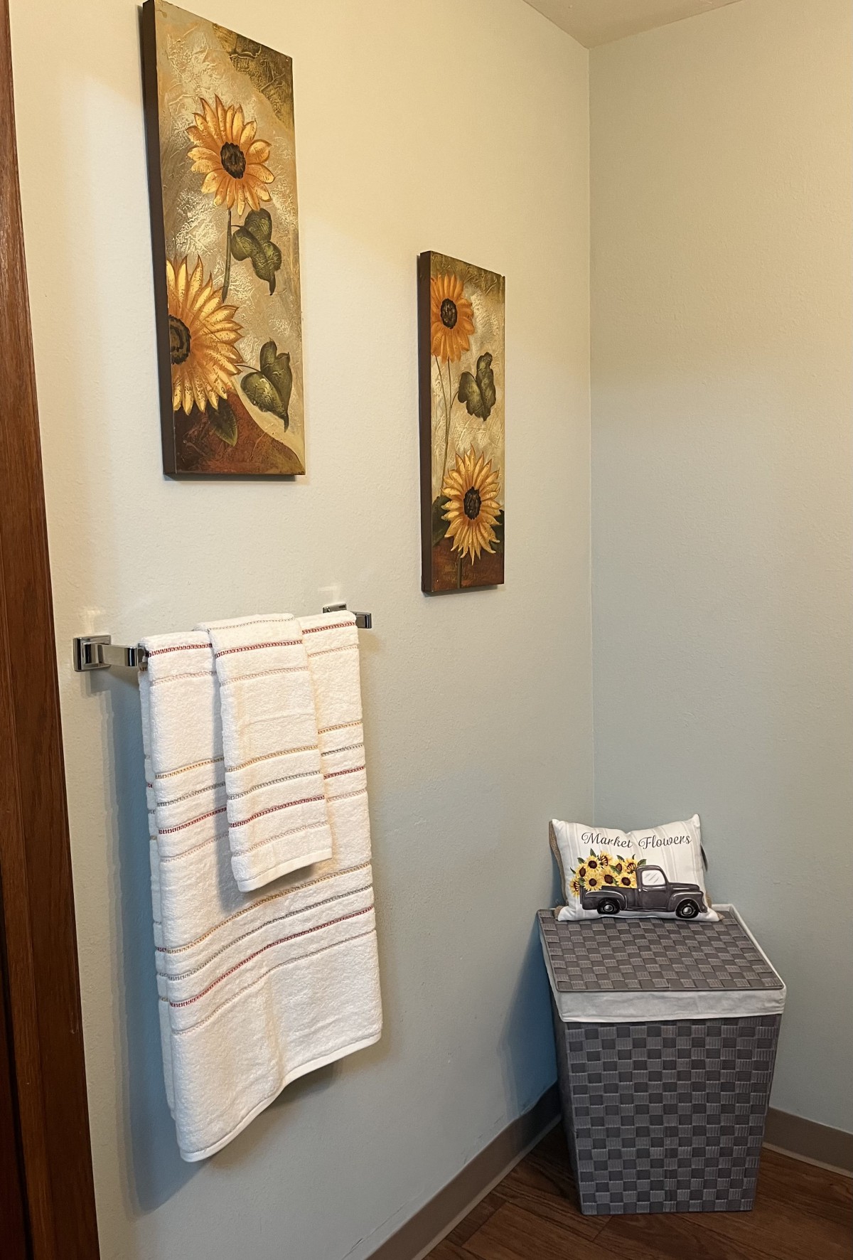 A well-decorated bathroom featuring sunflower artwork and neatly hung towels.