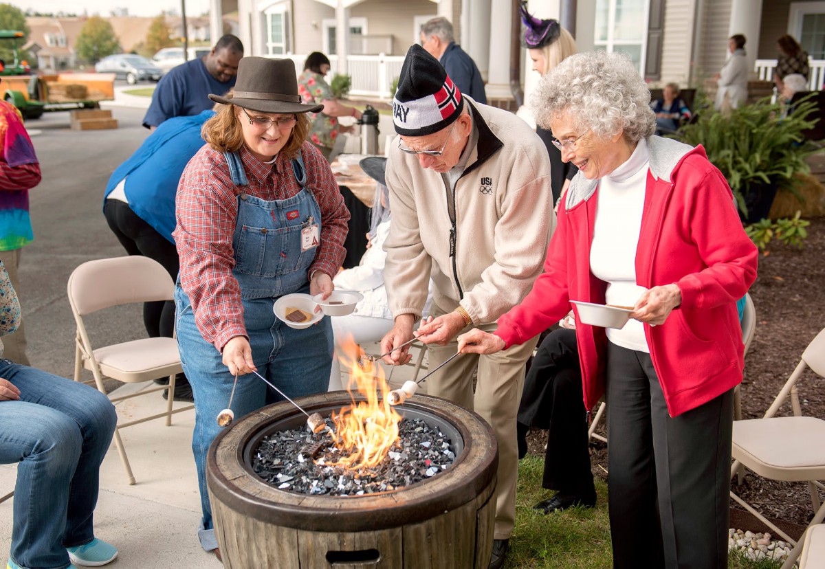 A group of people gathered around a fire pit, enjoying an outdoor cooking activity.