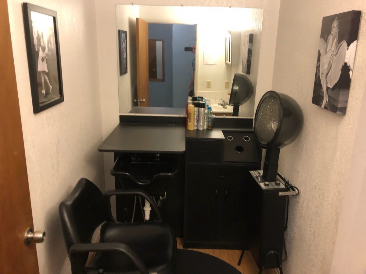 A small hair salon station with a mirror, chair, and hairdryer.