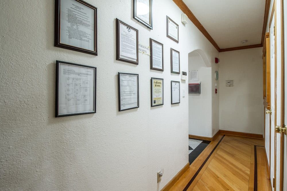 A hallway decorated with framed certificates and documents on the wall.
