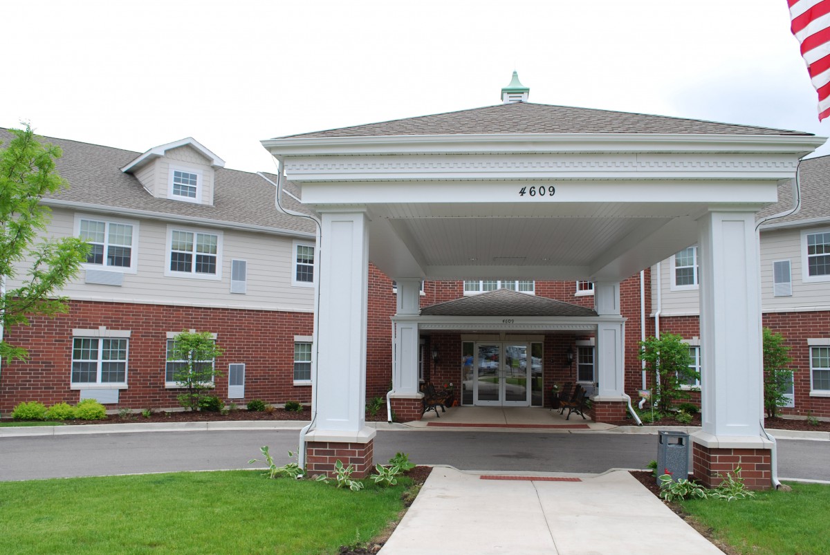 An entrance of a residential building with columns and a covered driveway.
