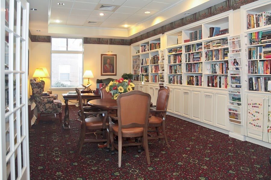 A cozy library room with bookshelves, tables, and chairs.