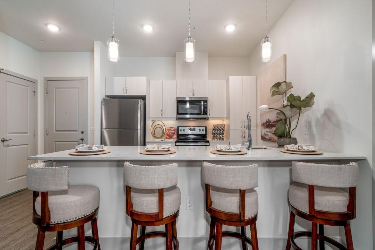 A sleek modern kitchen with stainless steel appliances, bar seating, and minimalist decor.