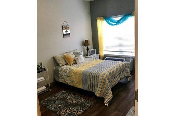 A cozy bedroom with a neatly made bed, accent pillows, and stylish decor.