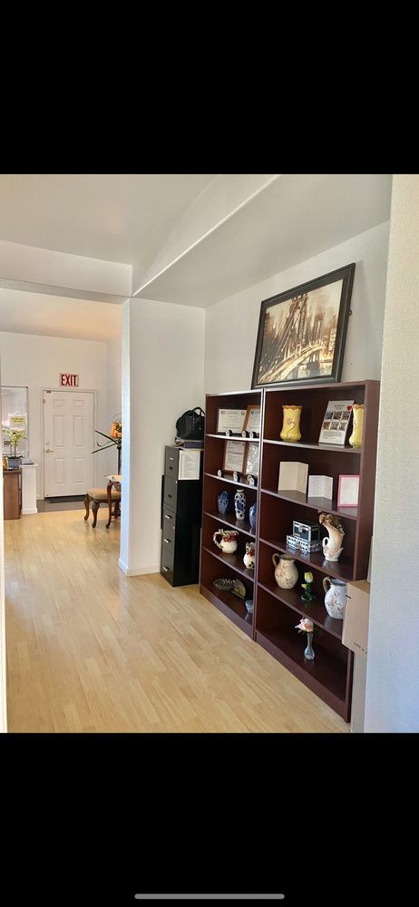 A cozy room featuring a bookshelf adorned with various vases and decor items, complemented by a painting above it.