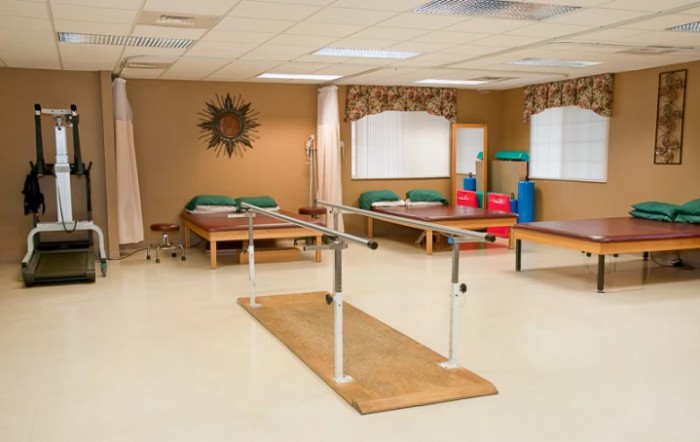 A rehabilitation room equipped with parallel bars and treatment tables for physical therapy.