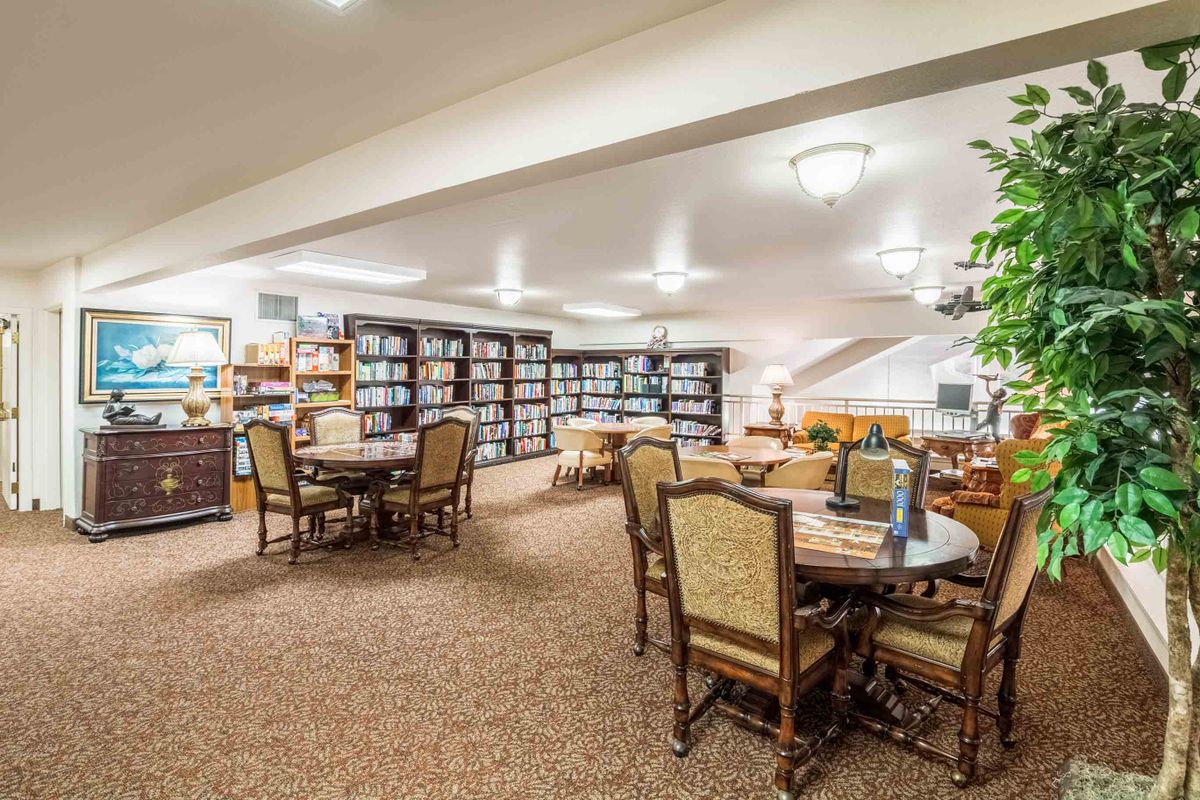 A cozy library with rows of bookshelves, tables, and chairs for reading.