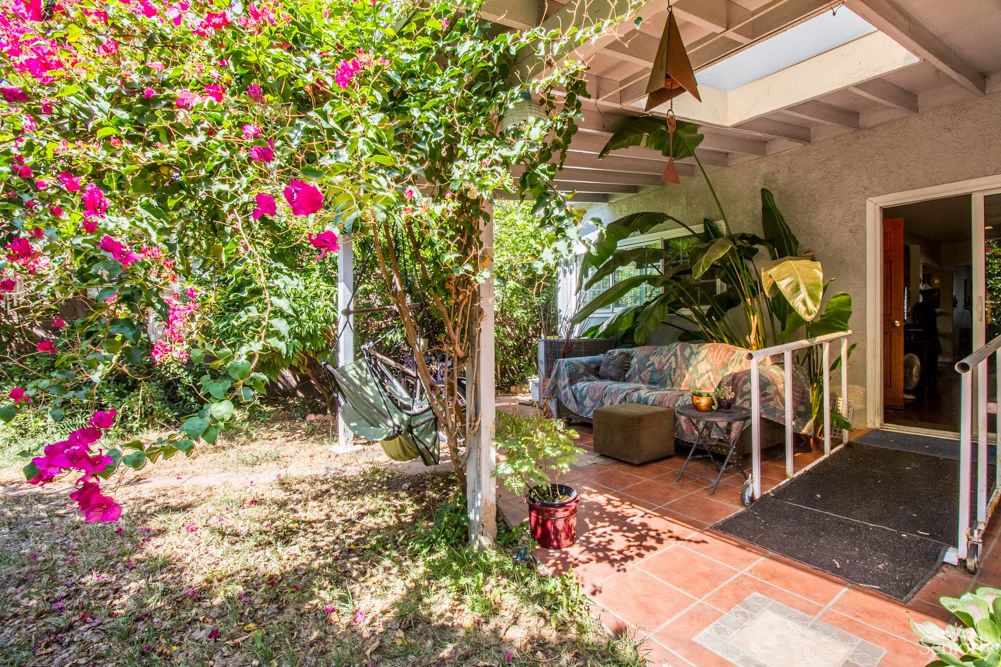 A cozy outdoor patio surrounded by lush greenery and vibrant flowers.