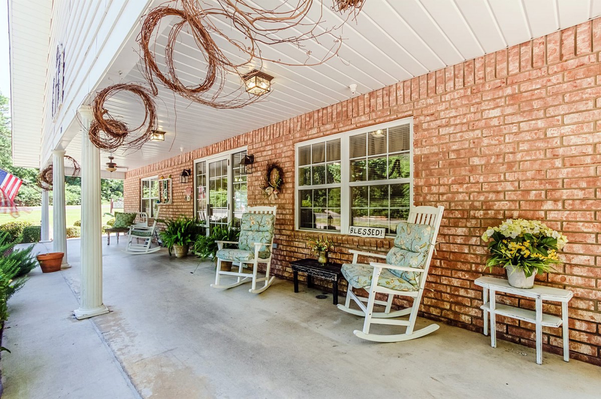 A cozy front porch with brick walls, featuring rocking chairs and decorative elements.