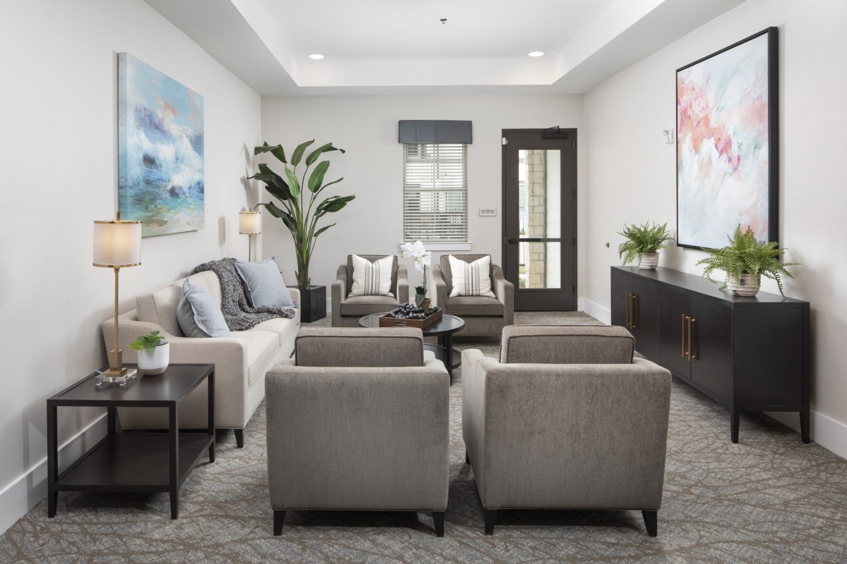 A modern living room featuring a comfortable sofa and armchairs, complemented by contemporary artwork and decor.