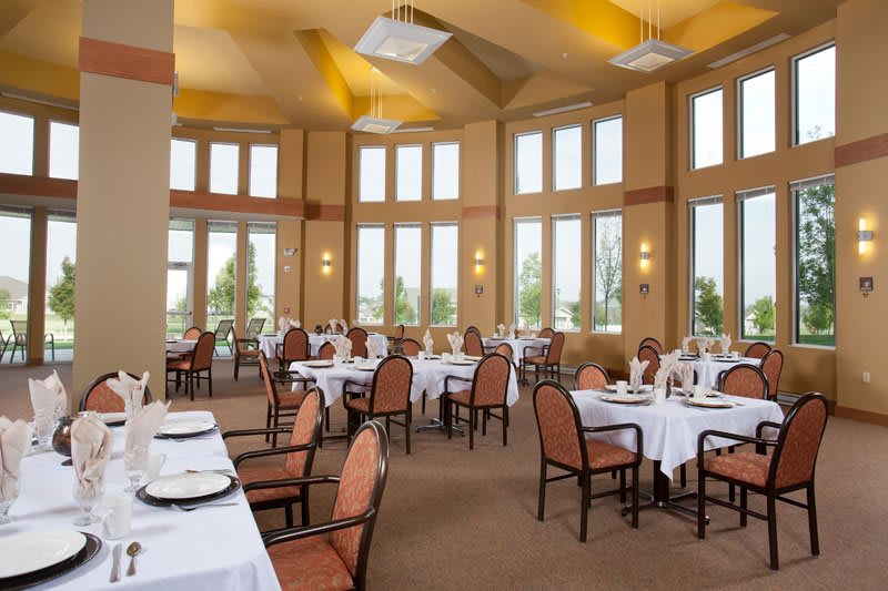 An elegant restaurant dining room with large windows and neatly arranged tables.