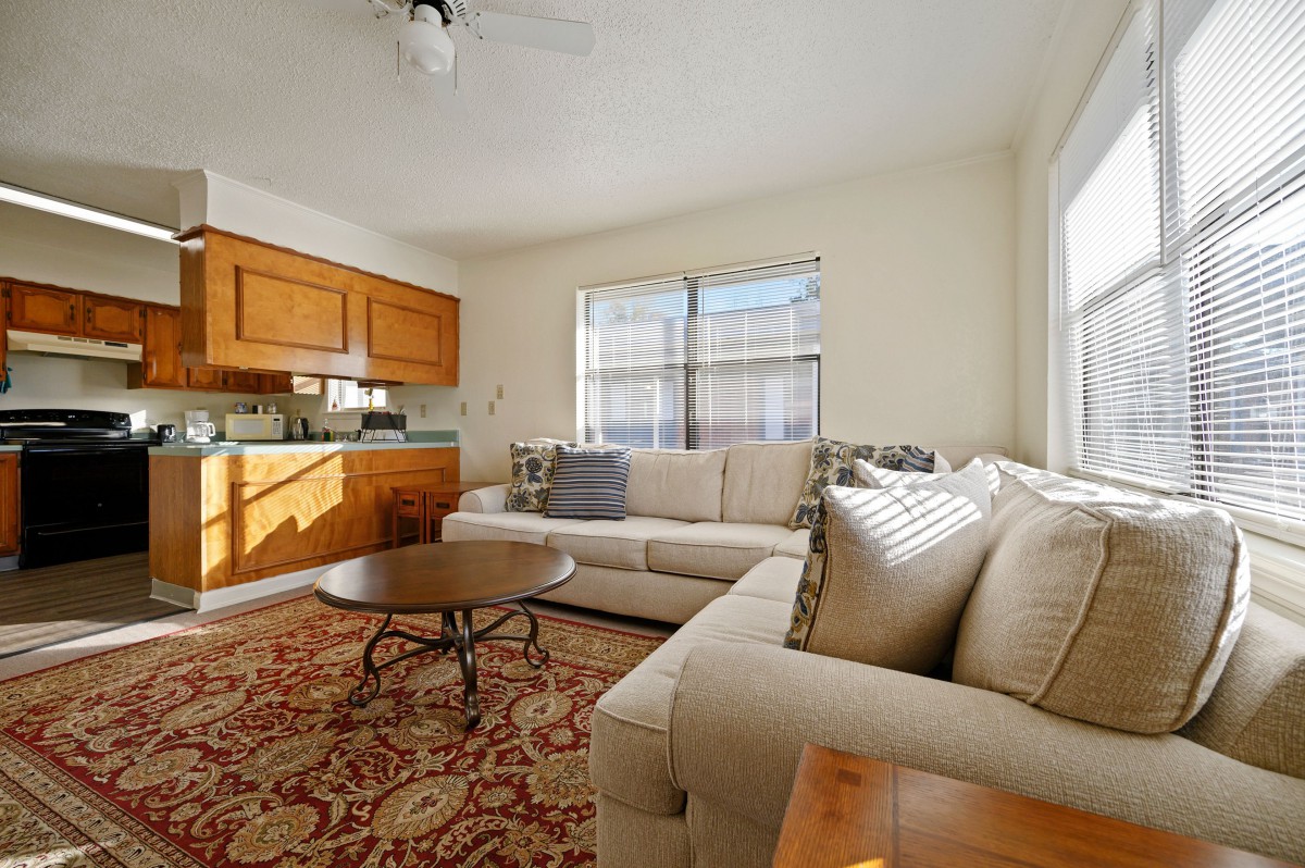 A cozy living room with a beige sofa, wooden cabinets, and a patterned rug.