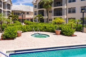 A beautiful resort setting with a swimming pool and jacuzzi surrounded by lush landscaping.