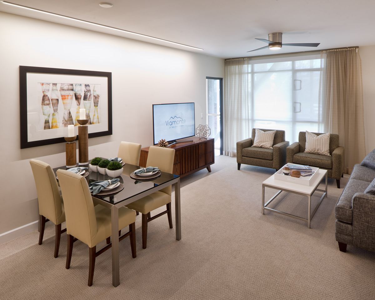 A modern living and dining area with neutral tones, featuring a television, stylish furniture, and wall art.