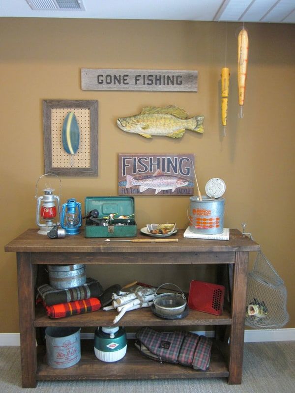 A rustic indoor display featuring fishing-themed decor and gear, including signs, a rod, and various accessories.