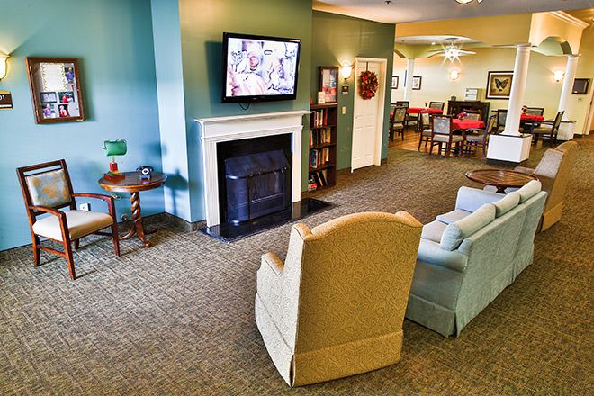 A cozy living room with a fireplace, television, and comfortable armchairs.