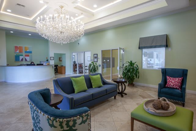 A well-furnished lobby with a chandelier, sofa seating, and a reception desk.