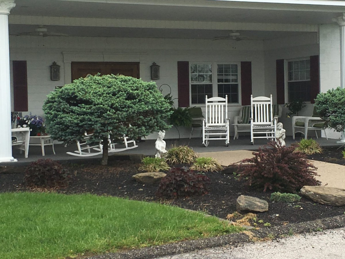 A cozy porch with white rocking chairs overlooking a well-maintained garden.
