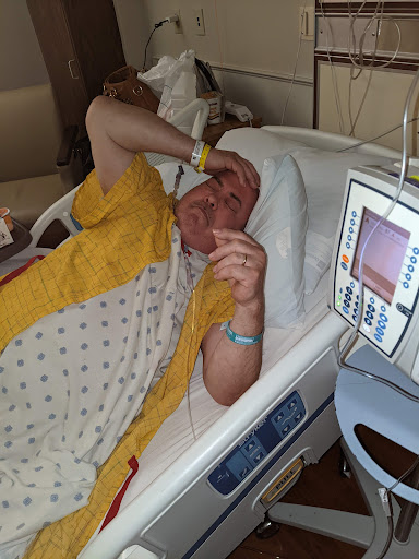 A patient resting in a hospital bed, appearing to be in discomfort.