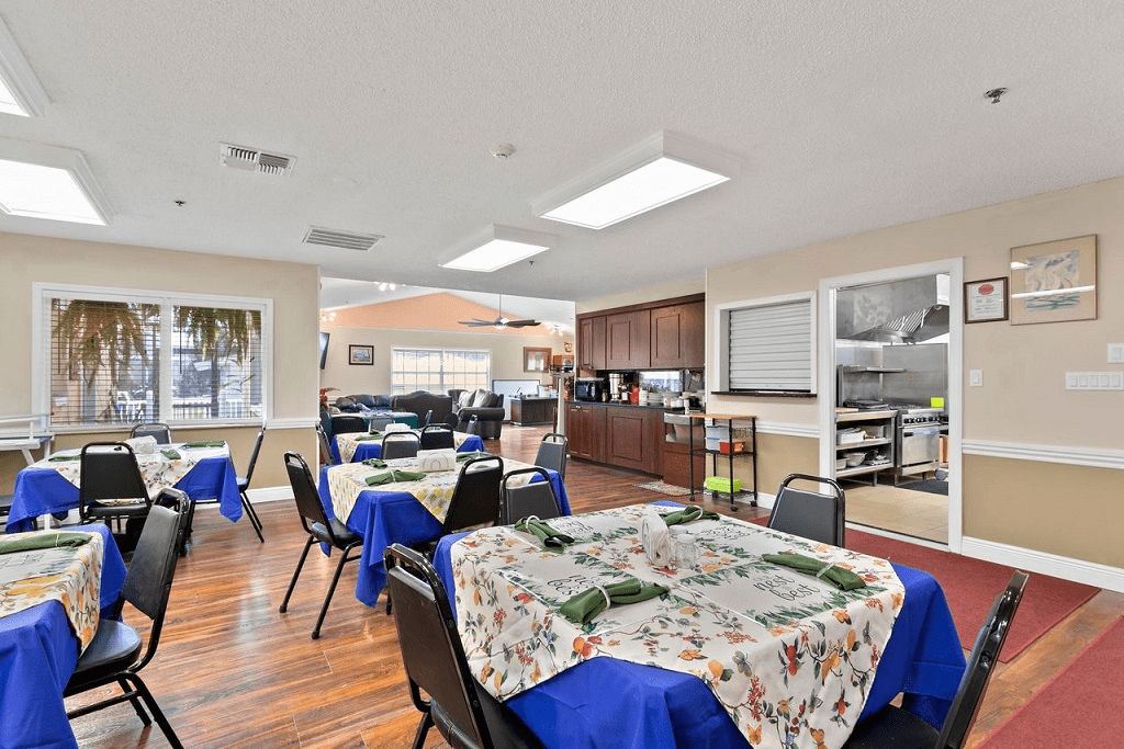 A well-lit dining area with neatly arranged tables and chairs, featuring decorative tablecloths.