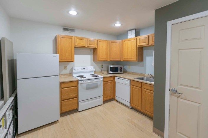 A modern kitchen with wooden cabinets and essential appliances including a refrigerator, stove, and microwave.