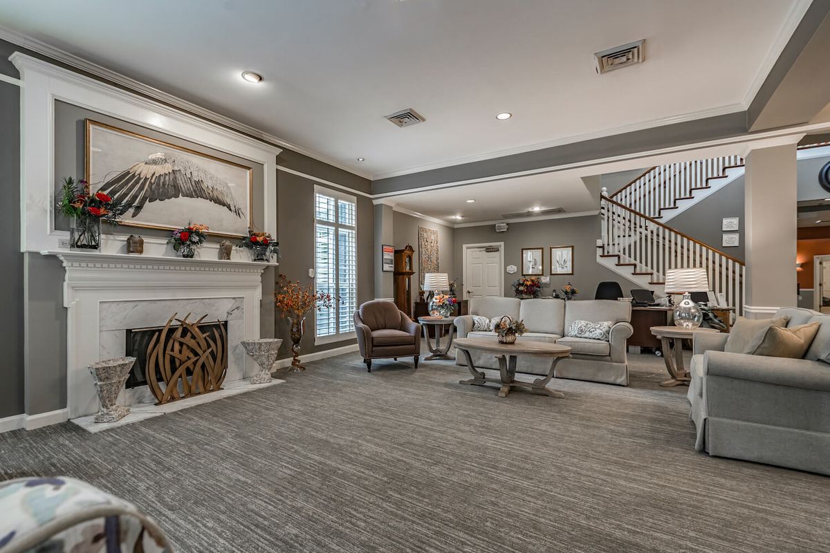 A spacious and elegantly designed living room featuring a fireplace, comfortable seating, and a modern staircase.