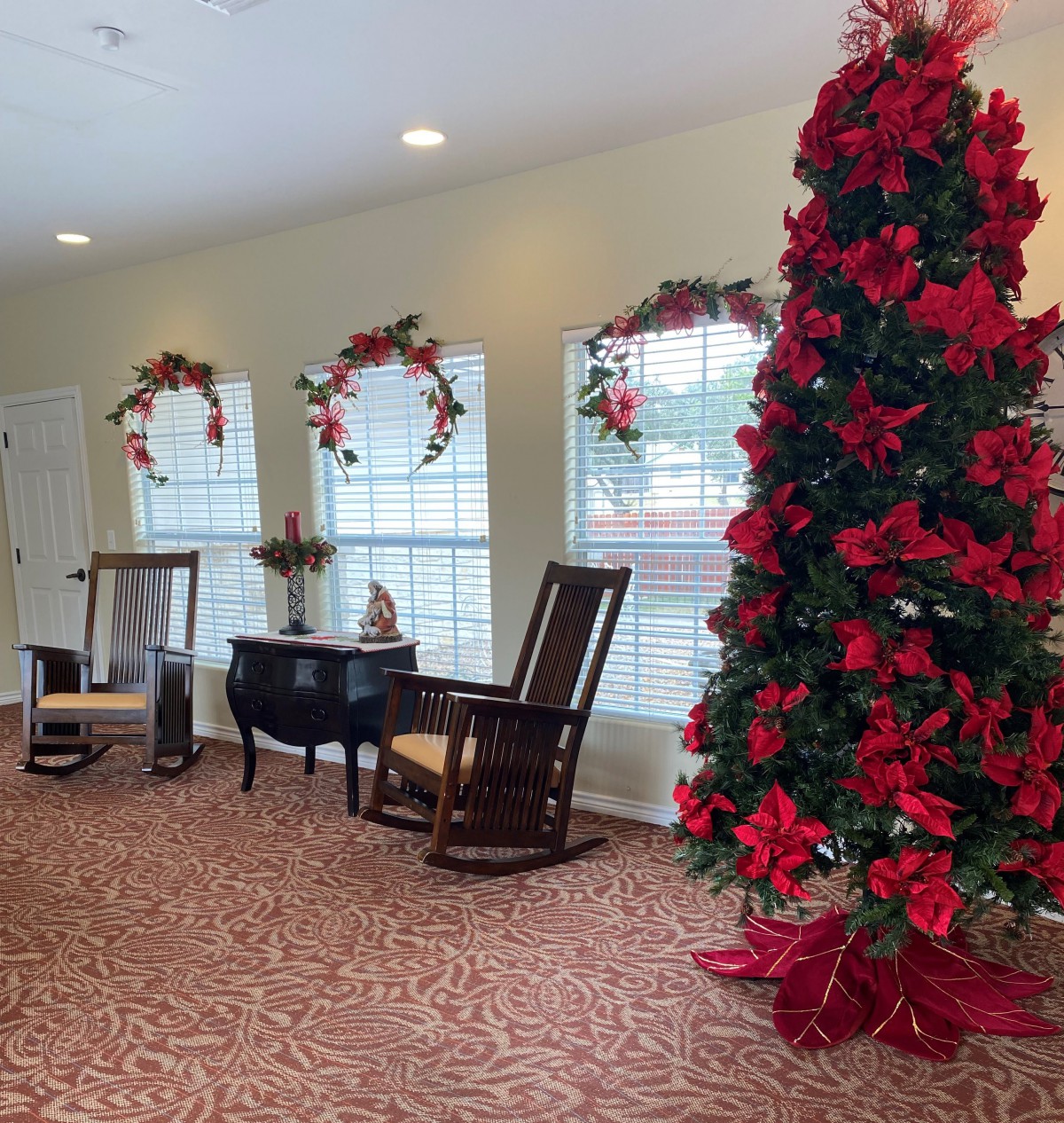 A cozy indoor setting with a beautifully decorated Christmas tree and rocking chairs by the window.