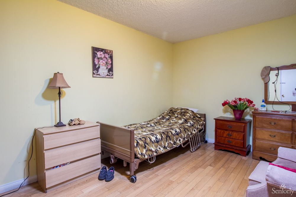 A simple bedroom with a single bed, dresser, and lamp.
