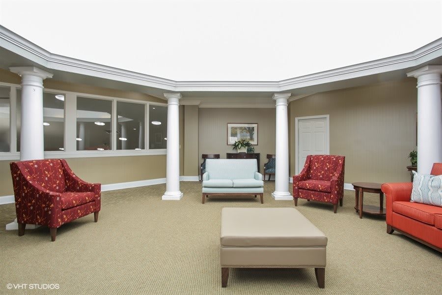 A spacious lobby area featuring comfortable seating with chairs and a sofa, complemented by decorative pillars.
