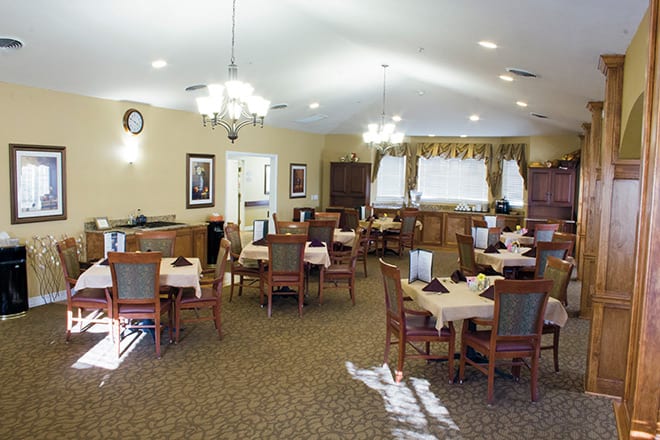 A cozy dining area with neatly arranged tables and chairs, featuring elegant lighting and decor.