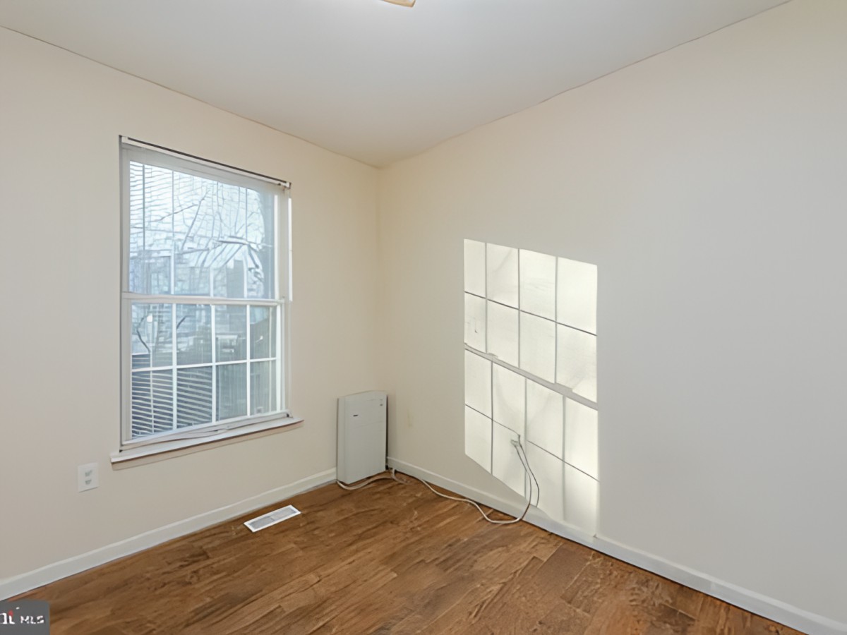 An empty room with sunlight streaming through a window onto the floor.