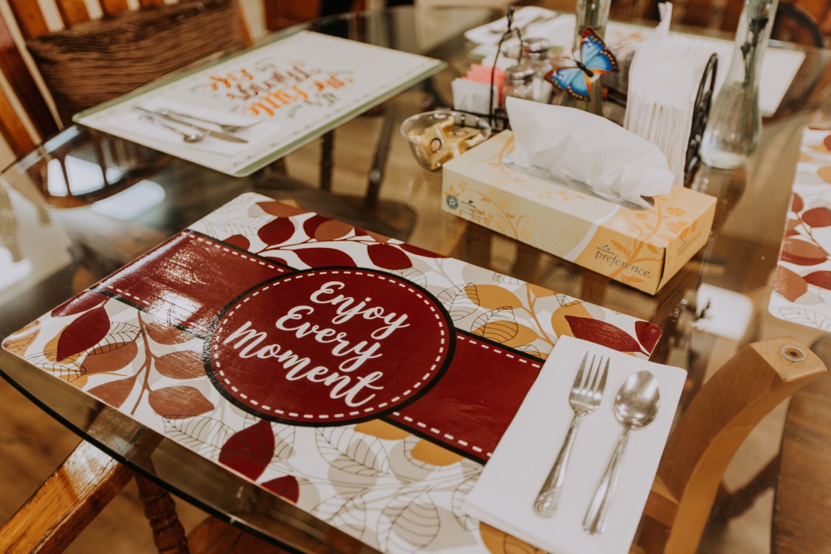 A beautifully set dining table with a colorful placemat and neatly arranged cutlery.