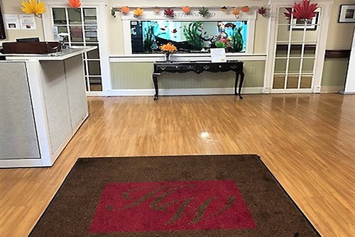 A welcoming reception area featuring a hardwood floor, decorative fish tank, and a simple table.