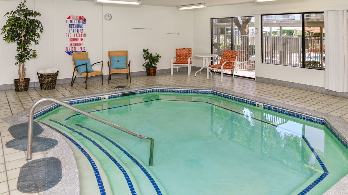 An indoor pool area with surrounding seating and tiled flooring.