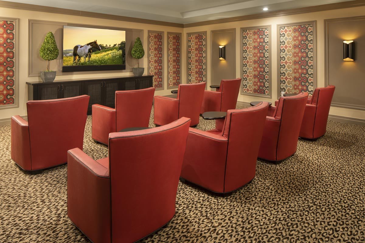 A modern home theater room with red chairs and a large screen on the wall.
